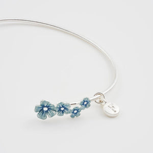 Side angle of Fable Forget-Me-Not Bangle with silver charm tag and detailed floral design.