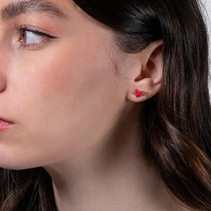 Model Wearing Earrings: A model wearing the Fable England Lovestruck Heart Earrings, showcasing their elegant red enamel heart and gold-tone arrow design.