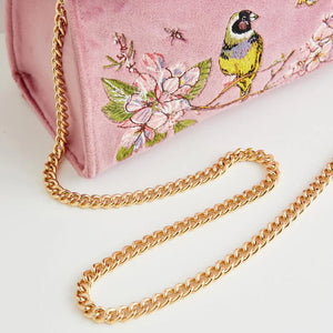 Close-up of the gold chain strap resting against the embroidered floral design, highlighting the luxurious details of the bag.