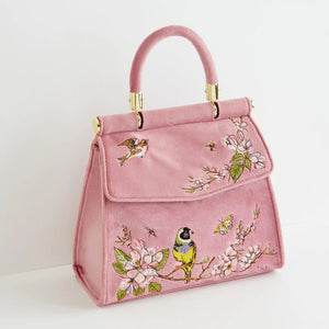 Angled side view of the Fable England Morning Song Mini Pink Tote, highlighting its structured shape, embroidered details, and elegant gold-tone hardware.