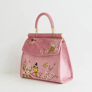 Three-quarter side view of the Mini Pink Tote, displaying the delicate embroidered birds, blossoms, and butterflies on the soft velvet exterior.