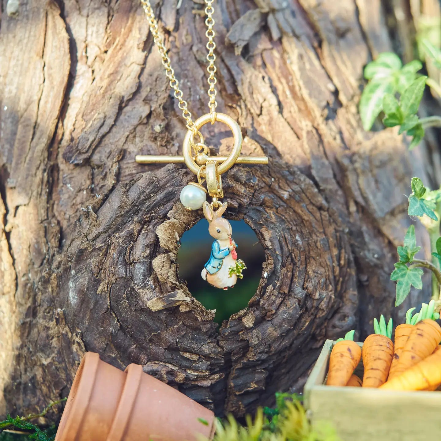 Peter Rabbit necklace styled on a tree, surrounded by carrots and miniature props.