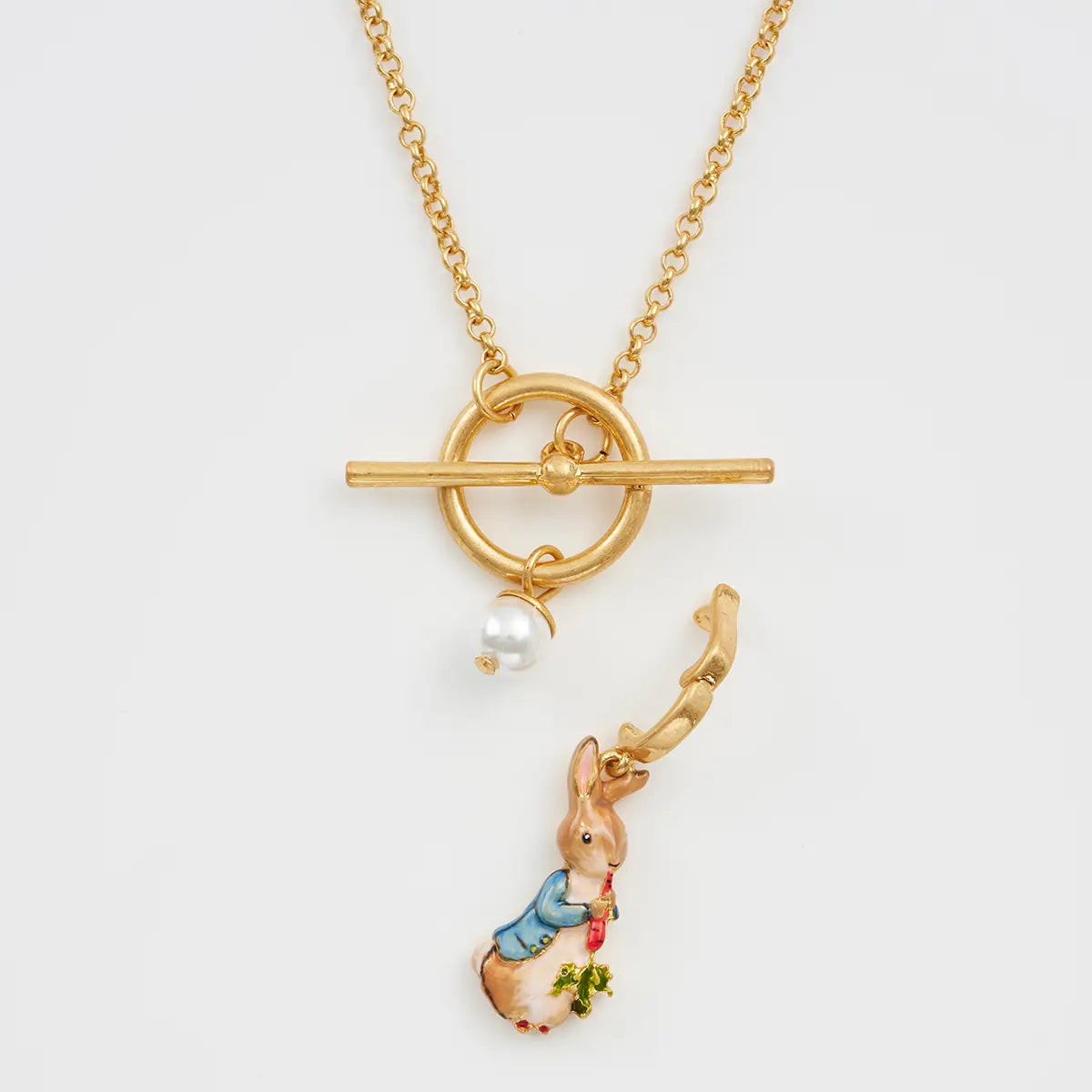 Detail shot showing toggle clasp, pearl charm, and Peter Rabbit pendant on gold necklace.