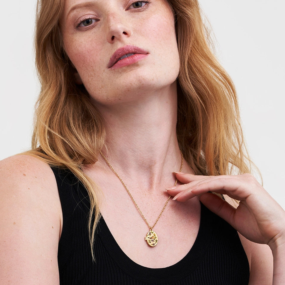 Model wearing Robin & Blackberry Gold Oval Locket Necklace on gold chain with enamel robin detail.
