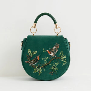 Fern green velvet saddle bag with embroidered robins on a branch, featuring a rounded silhouette and top handle.