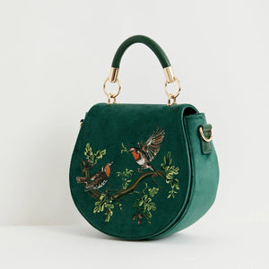 Side angle of robin embroidered green velvet saddle bag with gold hardware and curved design.