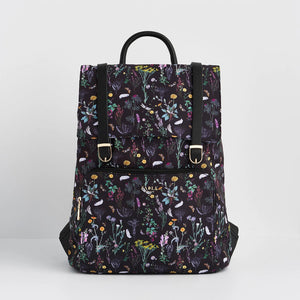 Front view of Fable England Wilderness Backpack with black background and multicoloured wildflower print, buckle detail and front zip pocket.
