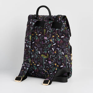 Angled rear view of floral Fable England backpack with ergonomic straps, top handle, and gold hardware detailing.