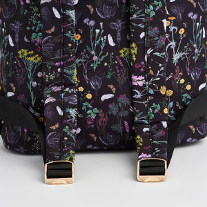 Bottom section of backpack showing padded floral straps with gold-tone buckles on black wildflower-printed fabric.