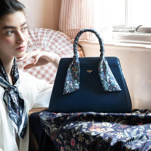 A woman in a vintage-inspired setting with the Wolf Garden tote placed on a patterned fabric, highlighting its elegant and artistic aesthetic.