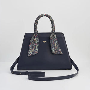 The Wolf Garden tote displayed with an adjustable navy blue shoulder strap, offering both handheld and crossbody styling options.