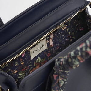 A close-up of the bag’s interior, showcasing the Wolf Garden print lining, a secure gold-tone zip closure, and Fable England branding.