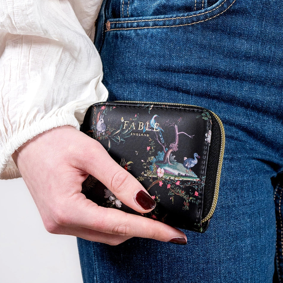 Model holding Wonderland Black Small Wallet by Fable England – compact size fits perfectly in hand.