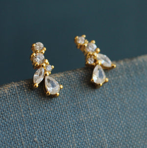 Close-up of Fairy Wing Tiny Petal Leaf Stud Earrings on fabric background, showcasing sparkling cubic zirconia stones.