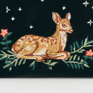 Close-up of embroidered fawn and foliage detail on green purse.