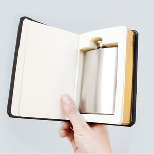 Hand holding open “Good Book” novelty flask gift, revealing the concealed stainless steel hip flask fitted snugly into the carved book interior.