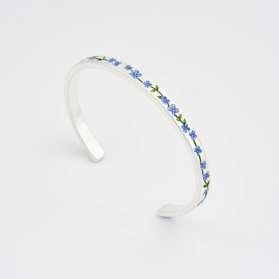 Sterling silver bangle with delicate forget-me-not flower charm on plain white background.