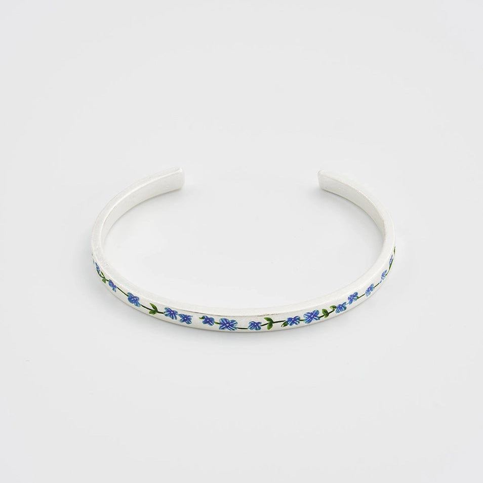 Close-up of forget-me-not charm detail on handcrafted silver bangle