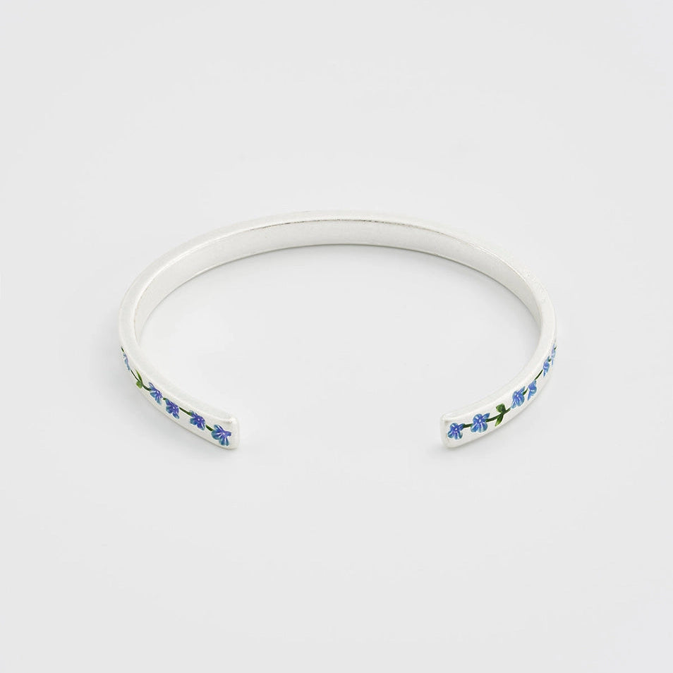 Side angle of sterling silver bangle with floral charm, showing hammered texture.