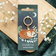 Freddie Fox enamel keyring displayed on illustrated forest-themed backing card with moon and foliage.