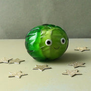 Front view of glass Brussels sprout ornament with googly eyes and festive sparkle.
