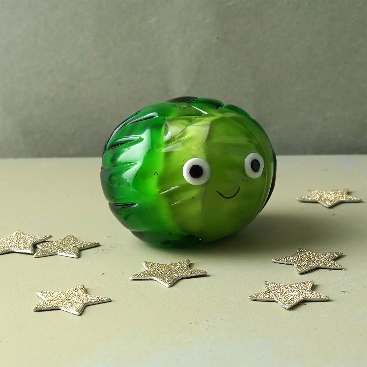 Front view of glass Brussels sprout ornament with googly eyes and festive sparkle.