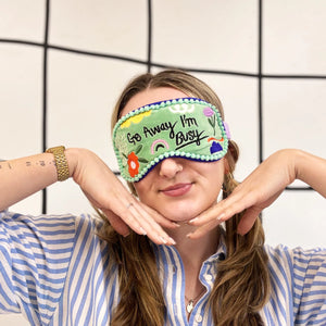 Go Away I’m Busy Eyemask worn by woman with striped shirt, smiling with hands under chin.