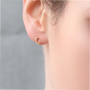 Gold vermeil moon stud earring worn on ear, showcasing its small size and subtle sparkle.
