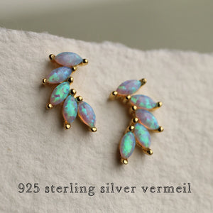 A close-up of gold vermeil opal wing stud earrings with shimmering blue and turquoise opals, set in 925 sterling silver with gold plating.