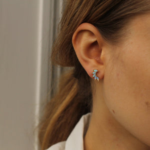 A model wearing gold vermeil opal wing stud earrings, highlighting their delicate, wing-like shape and iridescent glow.