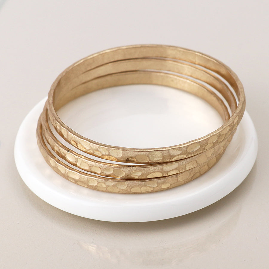 Close-up of faux gold triple bangle set with hammered texture.