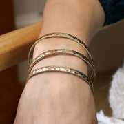 Golden worn bangles stacked on wrist with natural lighting.