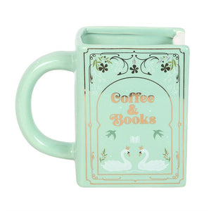 Green ceramic mug shaped like a book with floral and swan detailing.