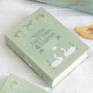 Green book-shaped storage box styled as “Myths, Fairy Tales, & Legends” on a bed.