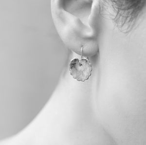 A black and white image of a model wearing the green clover leaf earrings, showing their elegant drop length and natural shape.