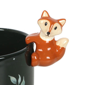 Close-up of cute 3D ceramic fox clinging to edge of dark green plant pot with painted moon and starry night theme