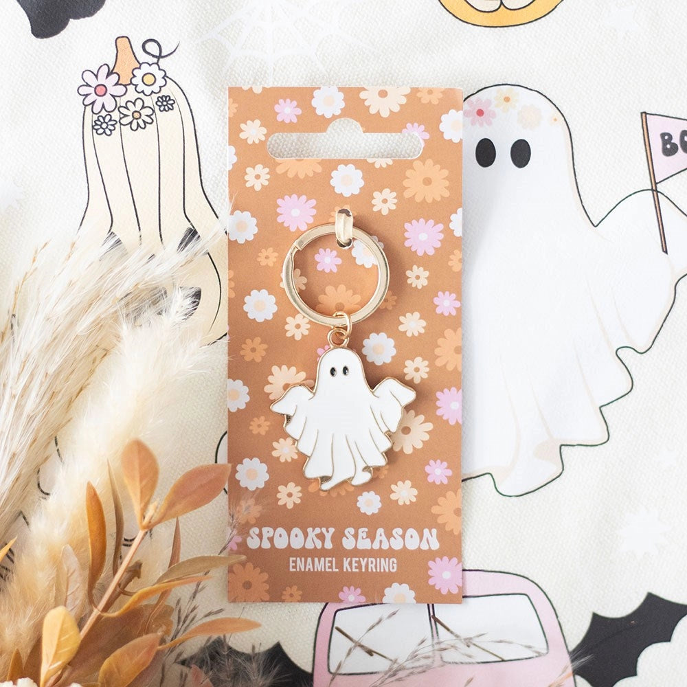 Groovy Ghost enamel keyring on retro floral backing card, styled with pampas grass and Halloween-themed fabric – cute spooky season gift idea