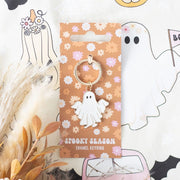 Groovy Ghost enamel keyring on retro floral backing card, styled with pampas grass and Halloween-themed fabric – cute spooky season gift idea