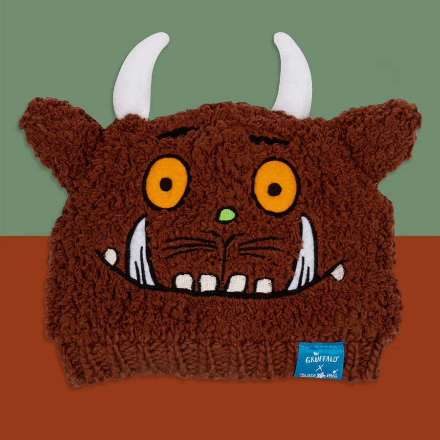 Gruffalo Winter Hat flat lay showing embroidered Gruffalo face, horns, and ears on brown knit background.