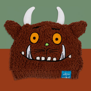 Gruffalo Winter Hat flat lay showing embroidered Gruffalo face, horns, and ears on brown knit background.