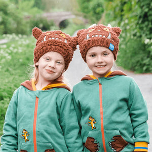 Two children wearing matching Gruffalo Winter Hats and green Gruffalo hoodies, holding hands outdoors.