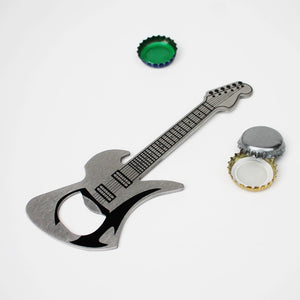 Metallic guitar-shaped bottle opener with two bottle caps on a white background