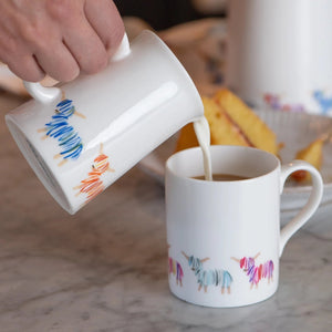 Pouring milk from the Highland Cow Jug into a matching mug.