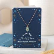 Hand of Hamsa necklace displayed on navy starry greeting card with envelope in background.