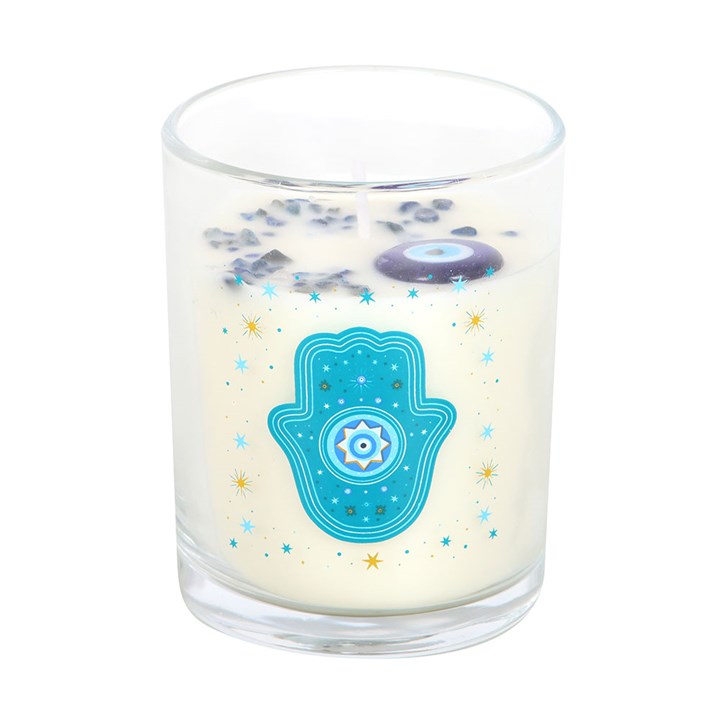 Glass jar candle with turquoise Hamsa hand and golden star accents on white wax.