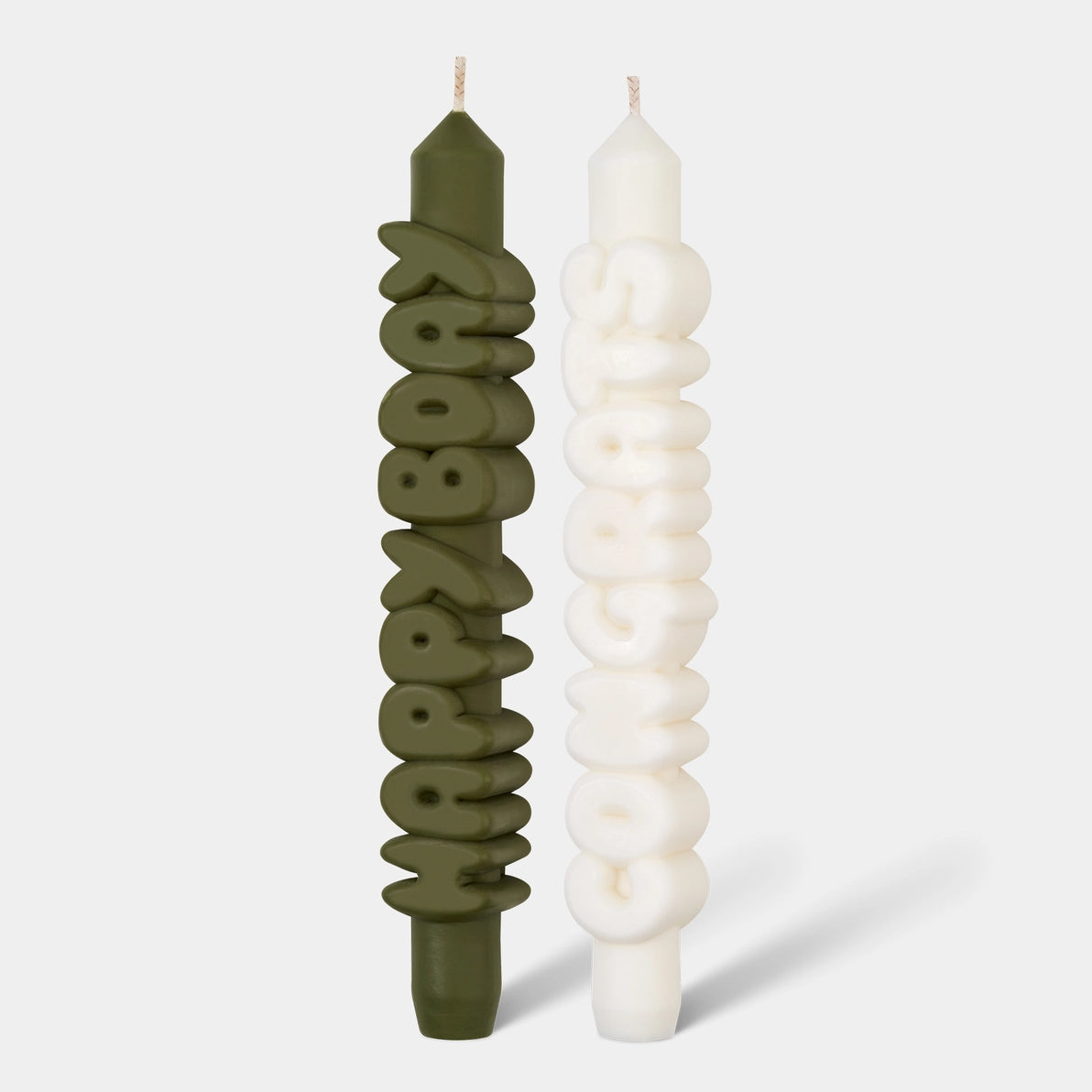 Front-facing view of two sculptural taper candles, one olive green with raised “Happy Bday” text and one white with raised “Congrats” text, displayed on a neutral background.