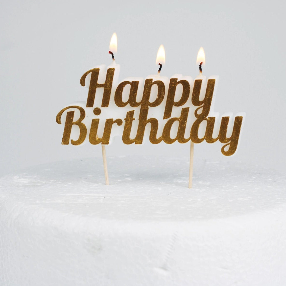 Lit Happy Birthday Cake Candle on a cake, creating a festive glow.