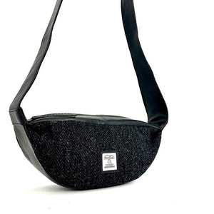 Front view: Harris Tweed Sling Bag in charcoal, highlighting the bag's dimensions, vegan leather trim and Harris Tweed Orb trademark badge.