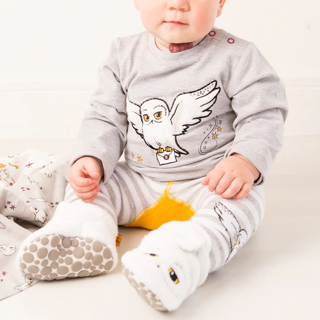 Baby wearing Harry Potter™ Hedwig Booties and matching Hedwig outfit while sitting indoors.
