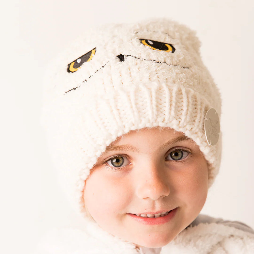 Smiling child in Harry Potter™ Hedwig Hat – cosy white owl beanie for kids.